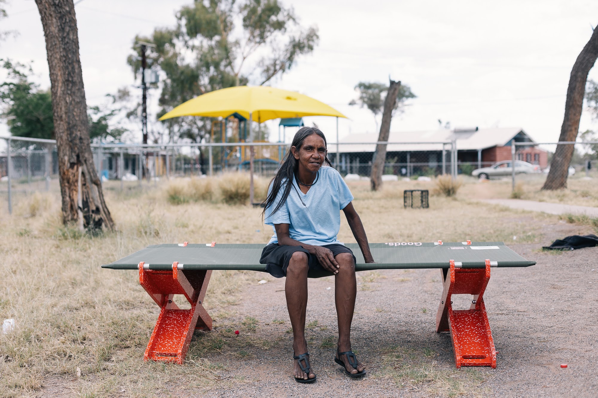 A woman sitting on a red Stretch Bed in a remote Australian community